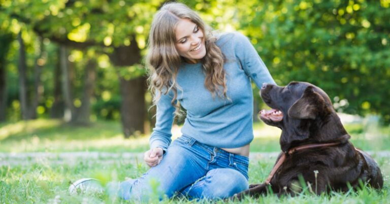 young woman in a park with her lab on a sunny day