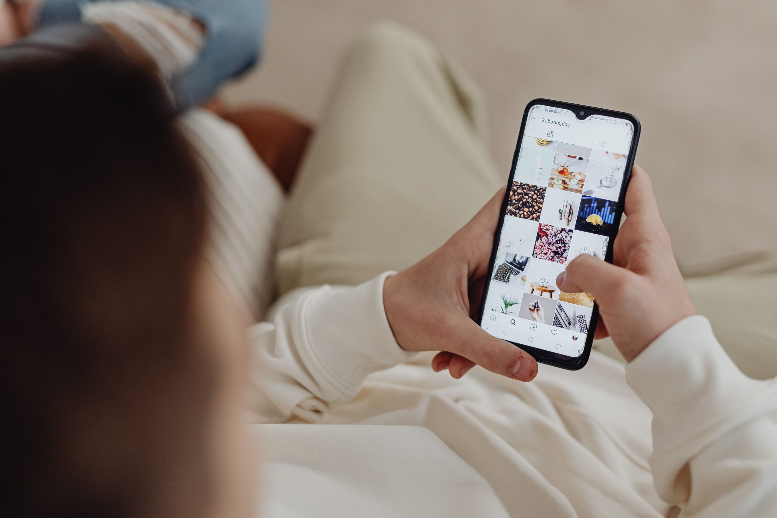 Person scrolling through social media on a smartphone, representing the performance of happiness online