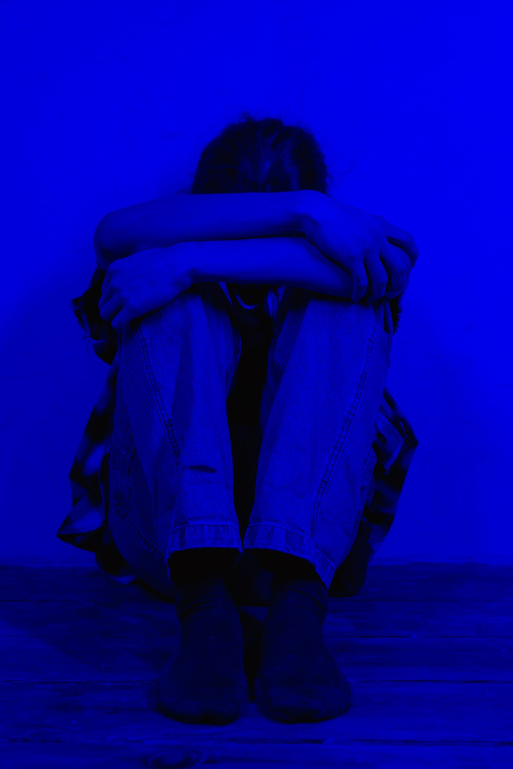 A person sitting alone on the floor in solitude, representing grief and sadness that gets silenced by forced positivity