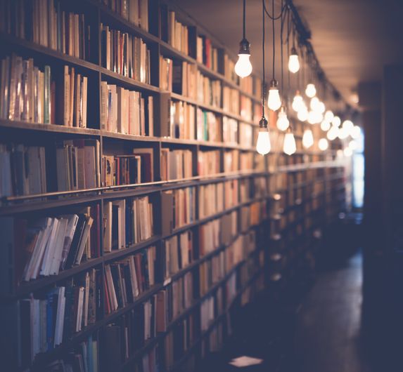 The Unbearable Lightness of Being Wrong: On the Ethics of Changing Your Mind 2 A warm library interior with rows of bookshelves
