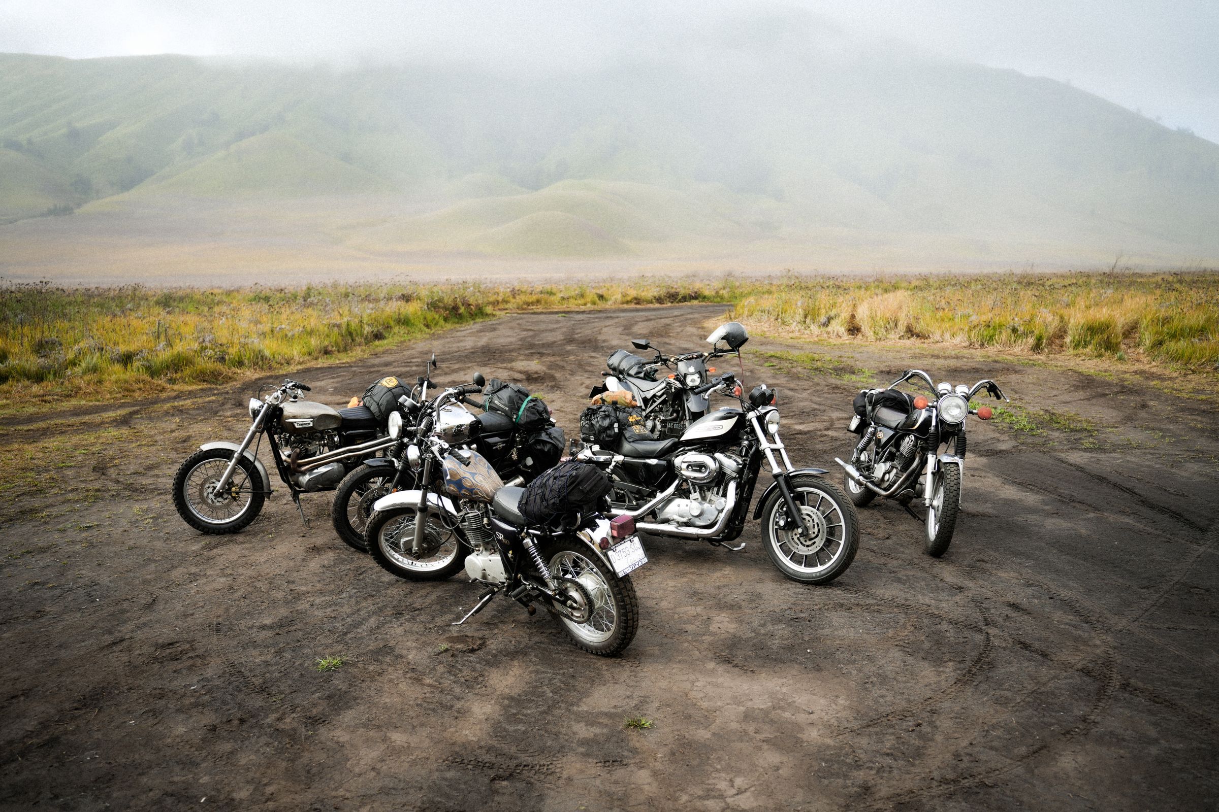 Five motorcycles parked together in a misty mountain landscape