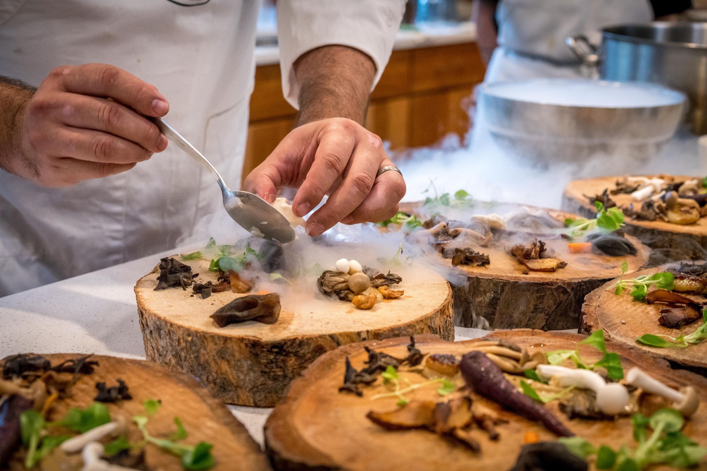 A chef carefully plating a dish on a wooden board, the craft that a star rating reduces to a number