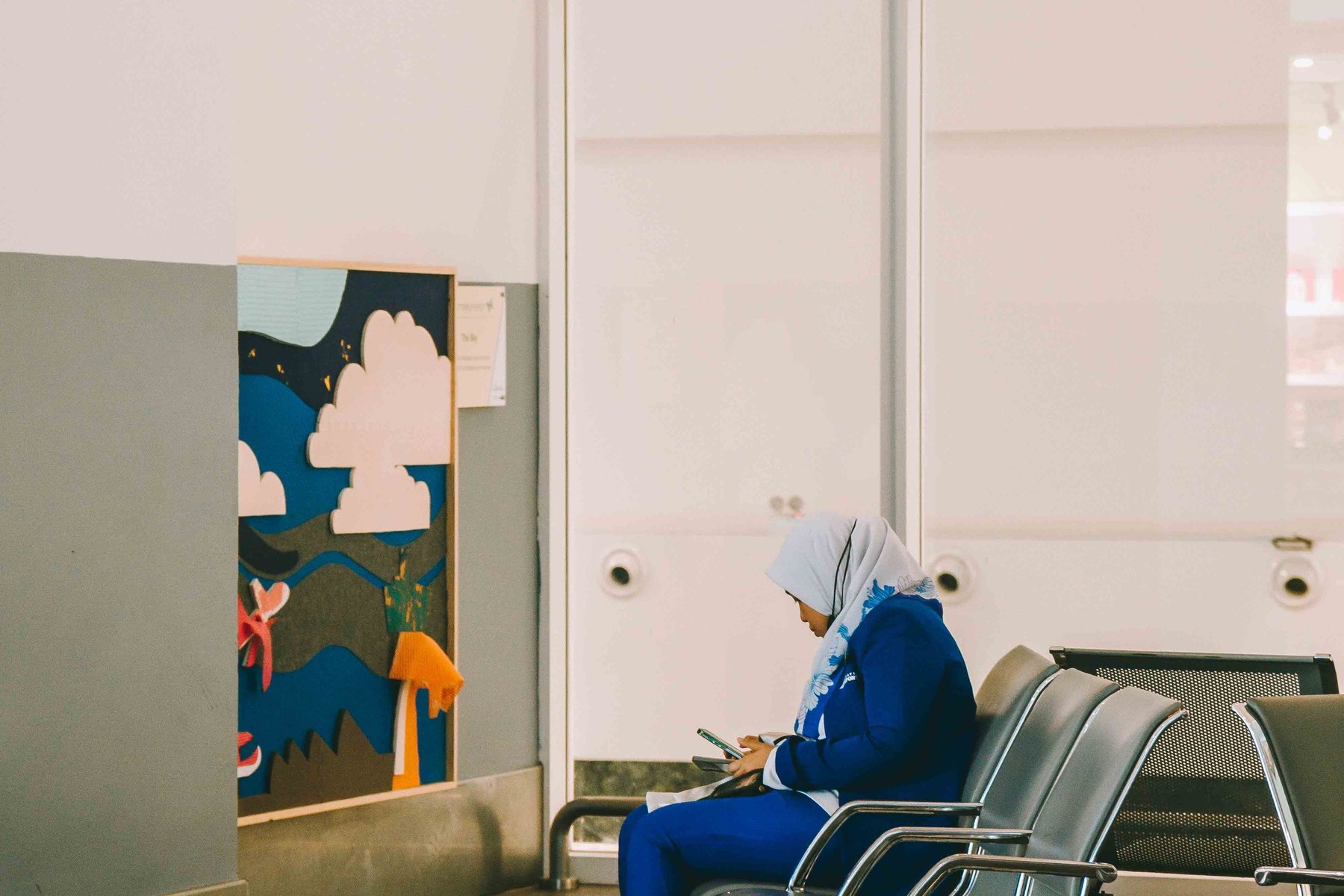 A woman checking her phone while seated in a waiting room, the read receipt as the digital equivalent of a glance at a watch