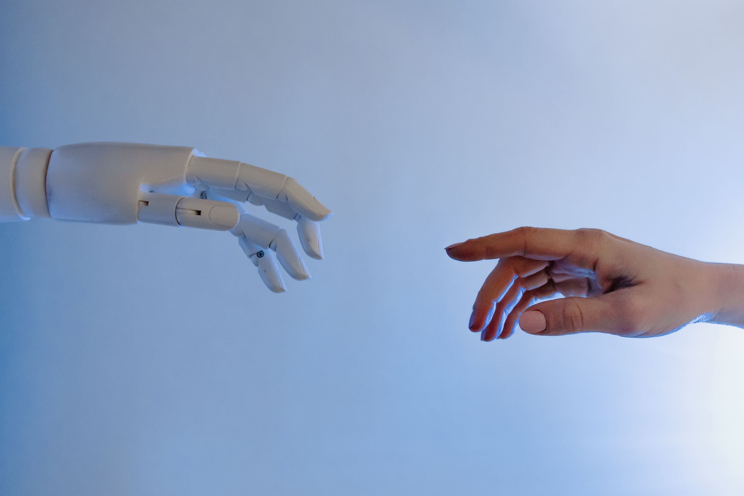 A human hand reaching toward a robotic hand, the trust we extend to machines that cannot earn it