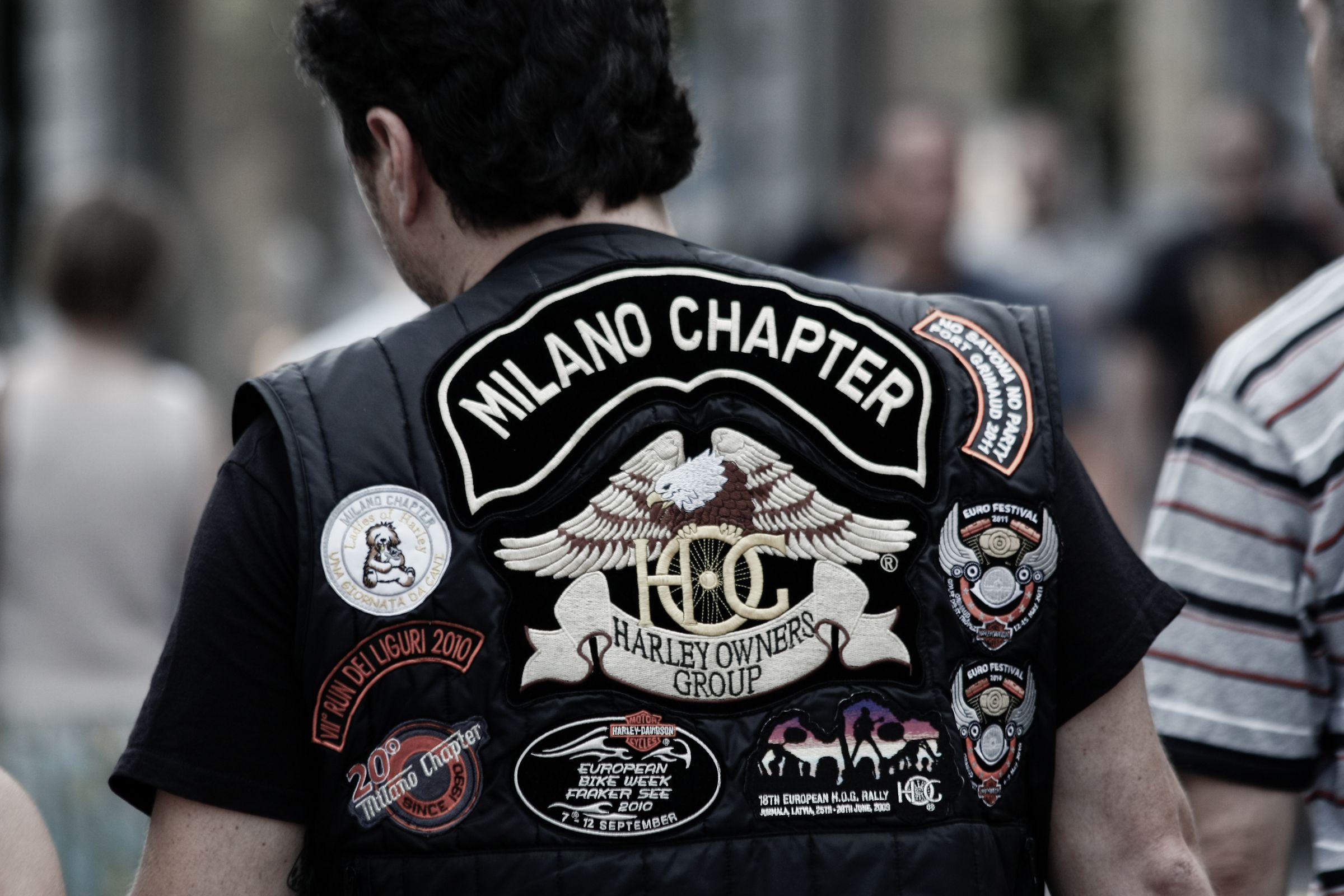 Back of a motorcycle club vest covered with sewn patches, the kind of membership marker that has to be earned