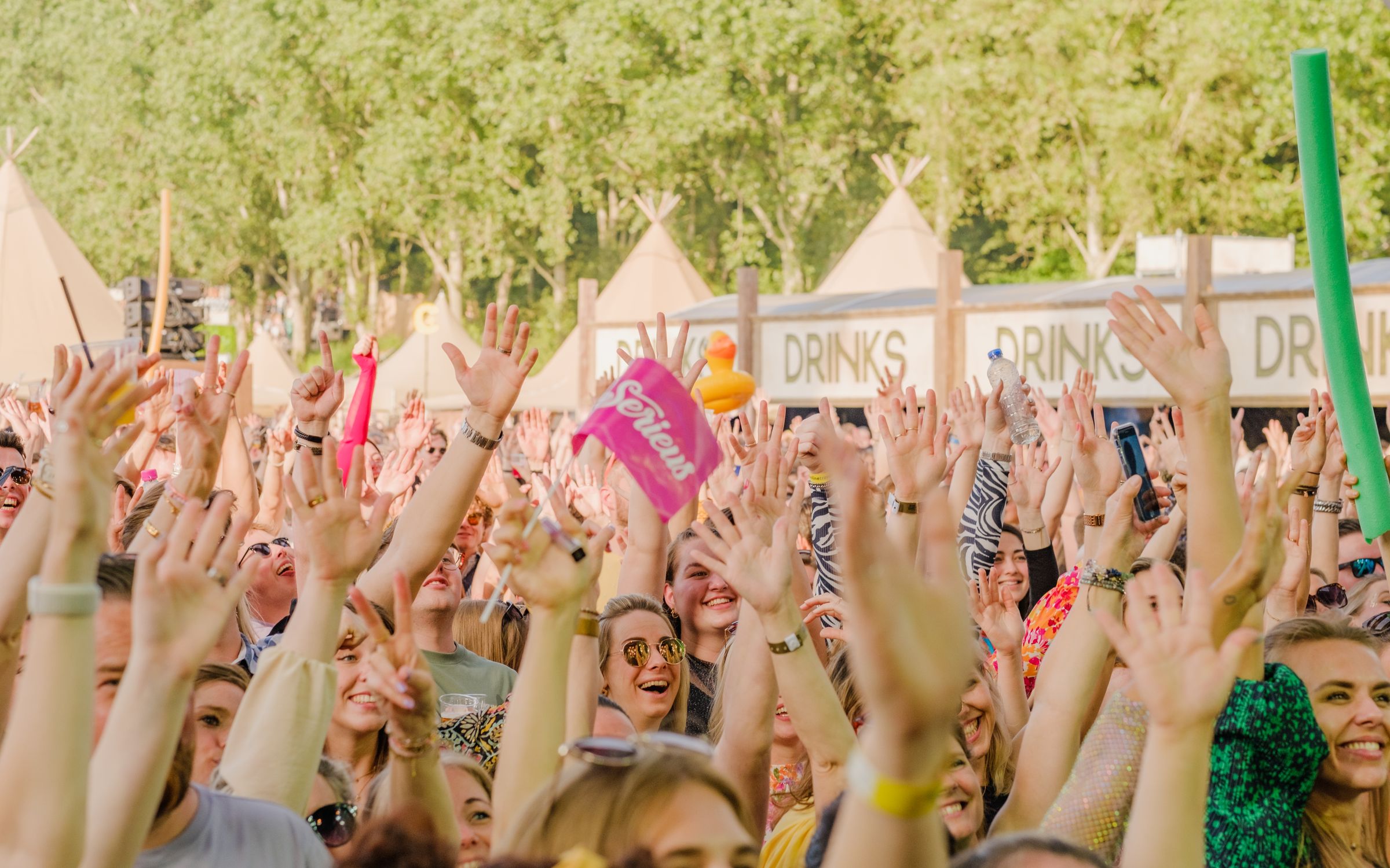 Concert crowd with hands raised in the air, people together inside a room that has a door