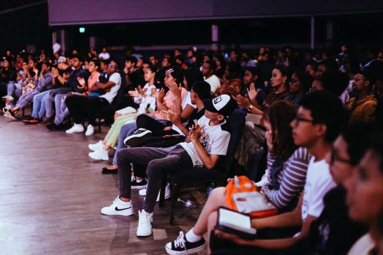 Audience seated in rows applauding at a live performance
