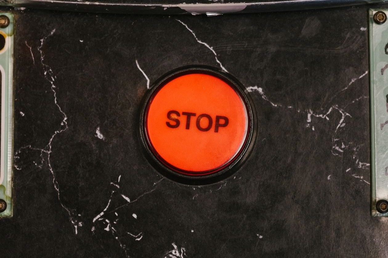 Close-up of a red stop button set into a dark machine panel