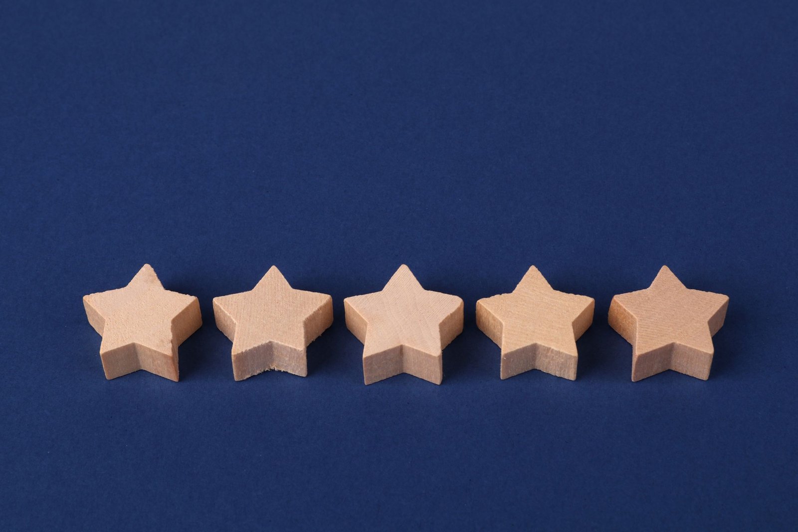 Five wooden star shapes laid in a row on a blue surface, the shape a rating takes when it stands in for a judgment