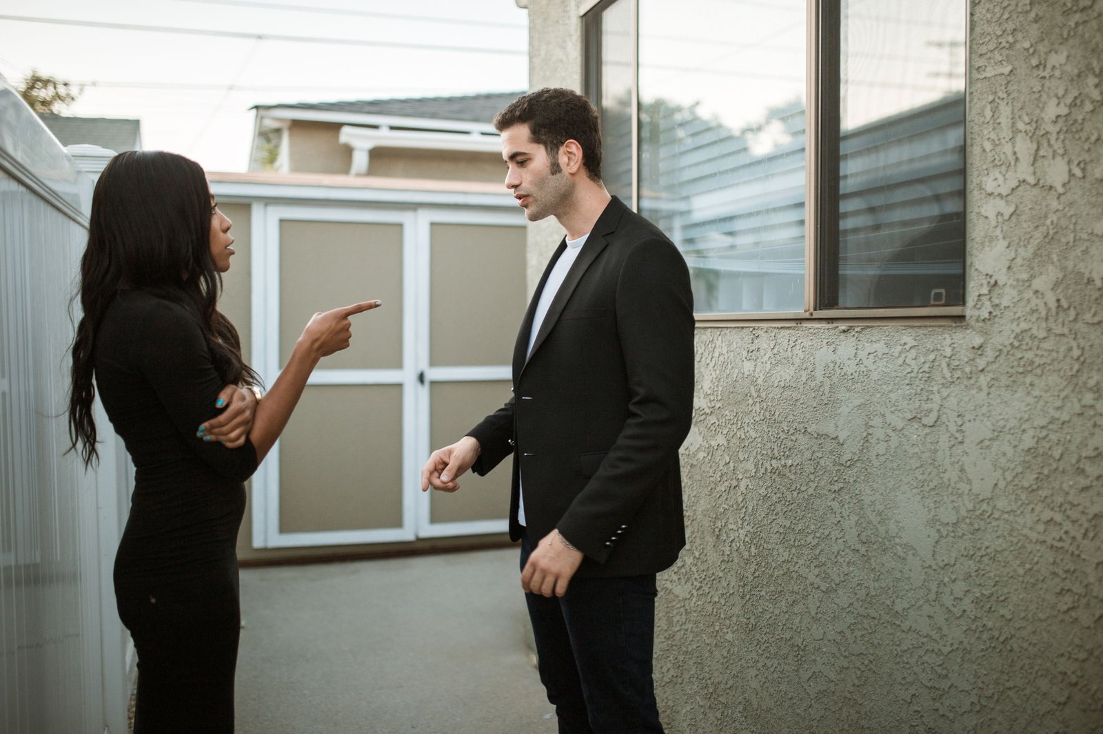 Two people arguing outdoors, one pointing a finger at the other