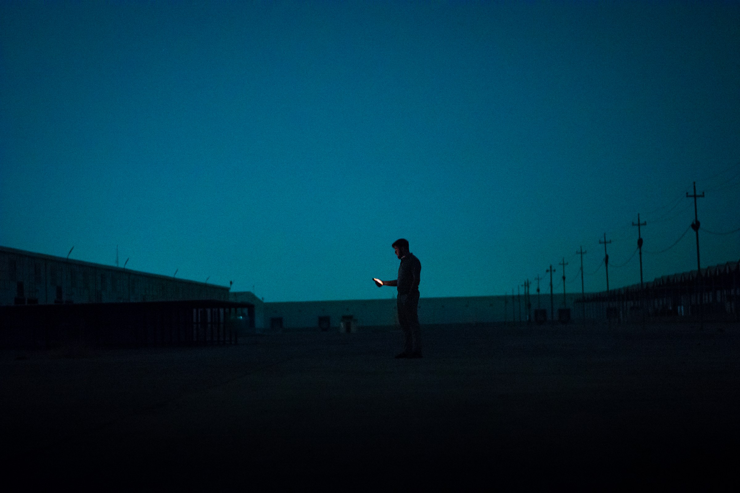 The Friend Who Cannot Disagree: On AI Chatbots, Delusion, and the Cost of Being Believed 2 A lone figure standing in a dark field at night, illuminated by the glow of a handheld phone
