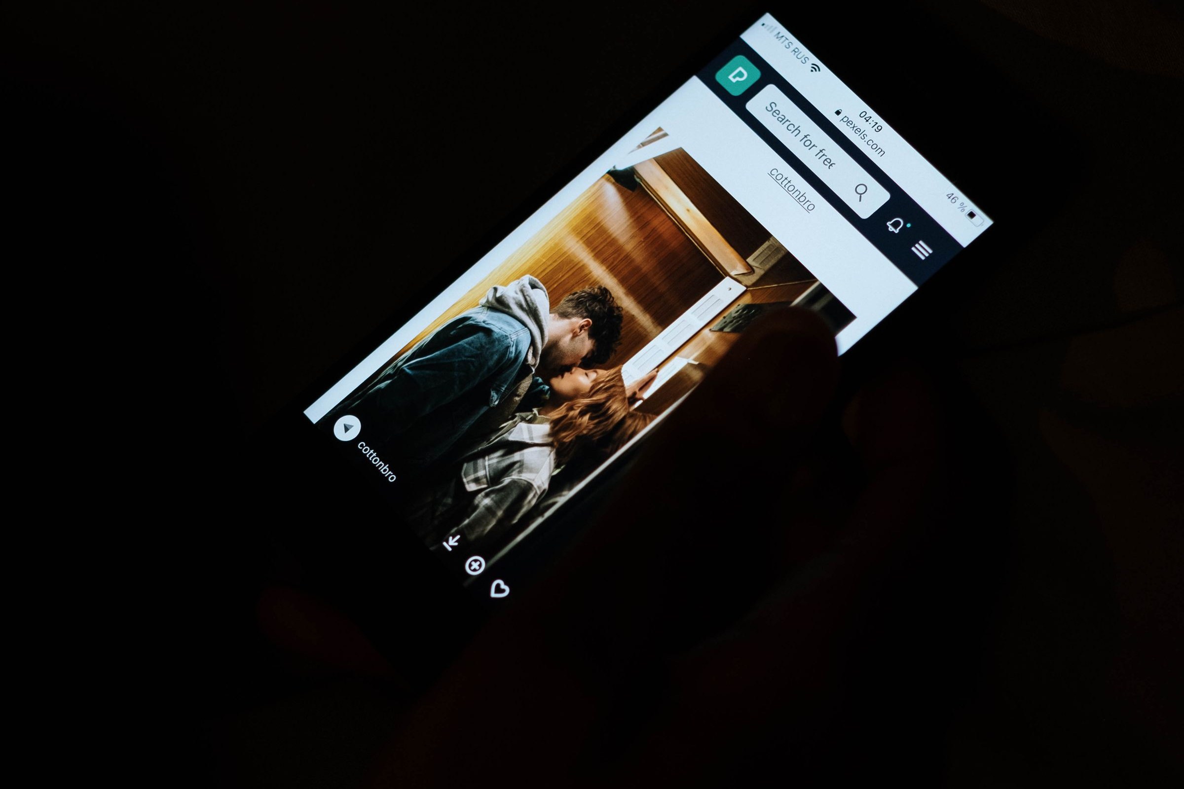 The Friend Who Cannot Disagree: On AI Chatbots, Delusion, and the Cost of Being Believed 4 A phone held in the dark showing an open chat conversation, the only light in the frame